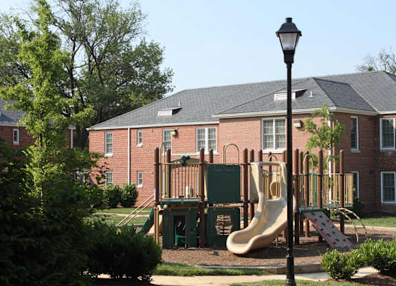 a playground in front of a brick building with a slide