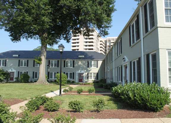 an exterior view of an apartment complex with a tree and a sidewalk
