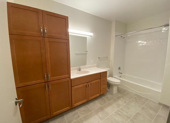 a bathroom with wooden cabinets and a toilet and a sink