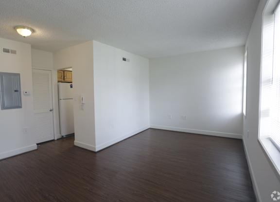 an empty living room with a wood floor and white walls