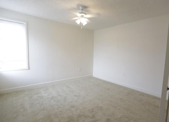 an empty living room with a ceiling fan and a window