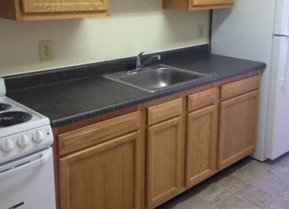 A kitchen with wooden cabinets and a white stove.
