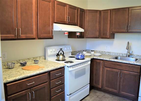 A kitchen with a white stove and brown cabinets.