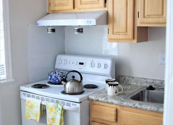 A white stove with a kettle on top and a pot on the stove.