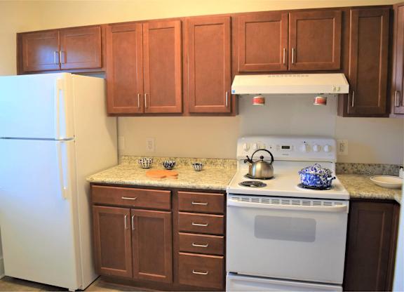 A kitchen with brown cabinets and a white stove.