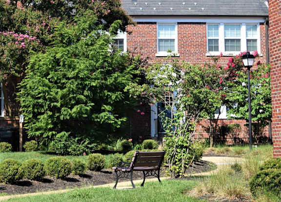 A red brick building with a black bench in front of it.