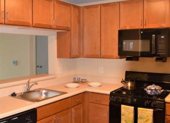 A kitchen with wooden cabinets and black appliances.