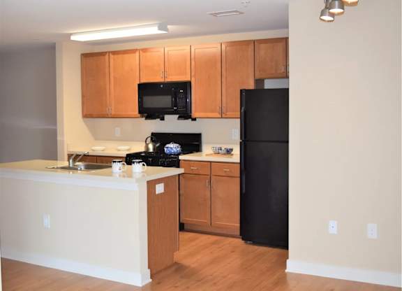 A kitchen with wooden cabinets and black appliances.