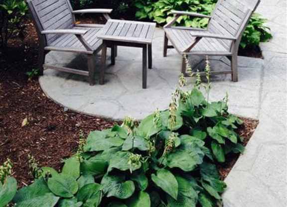 Two chairs and a table are in a garden.
