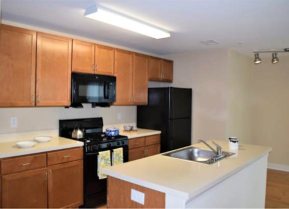 A kitchen with brown cabinets and black appliances.