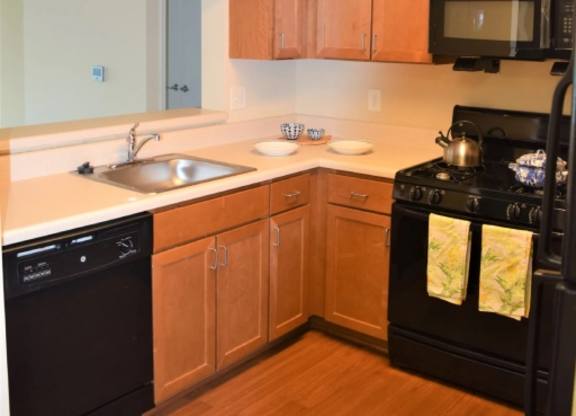 A kitchen with wooden cabinets and black appliances.