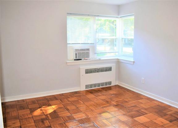 A room with a window and a radiator on the floor.