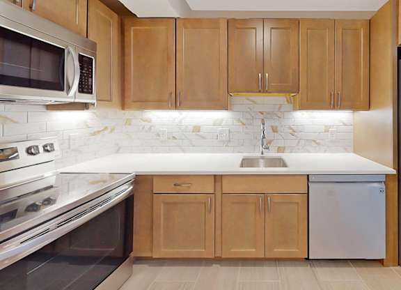 A kitchen with wooden cabinets and a marble backsplash.