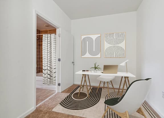 A white chair sits in front of a white table with a laptop on it.