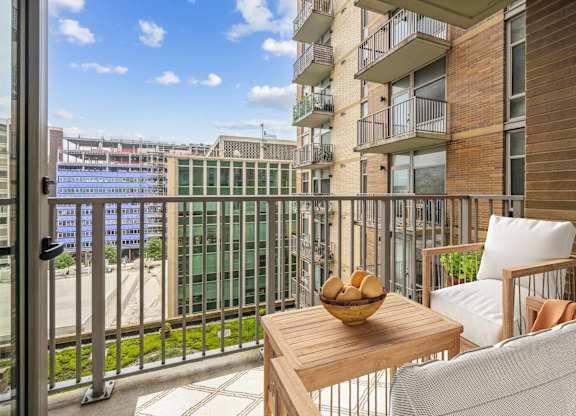 A balcony with a table and chairs overlooking a cityscape.