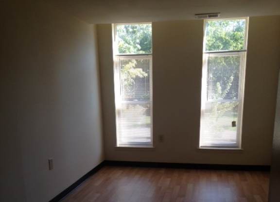 A room with wooden floors and two windows.