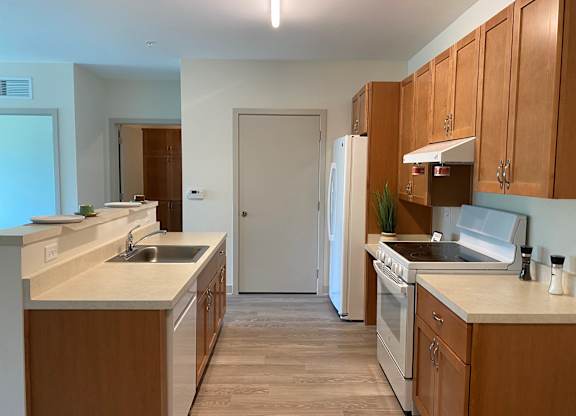 an empty kitchen with wooden cabinets and a white refrigerator