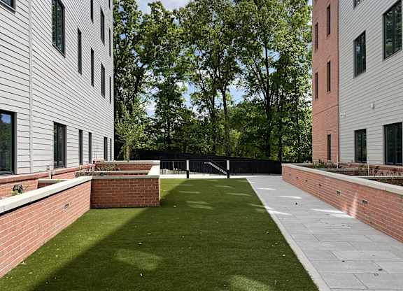 A grassy courtyard is surrounded by two buildings.