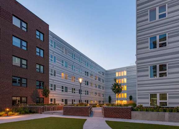 A modern building with a brick facade and a pathway leading to a courtyard.