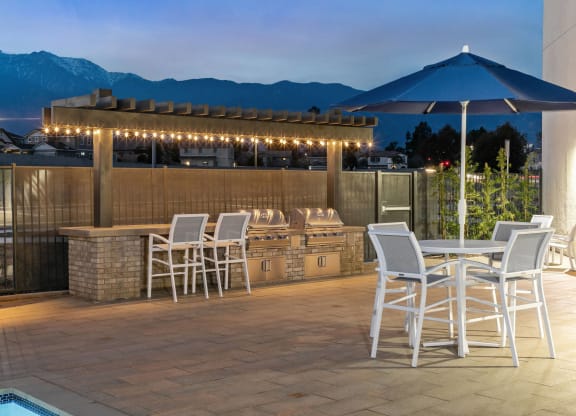 a patio with a bar and tables with chairs and umbrellasat Westbury Apartments, Rancho Cucamonga