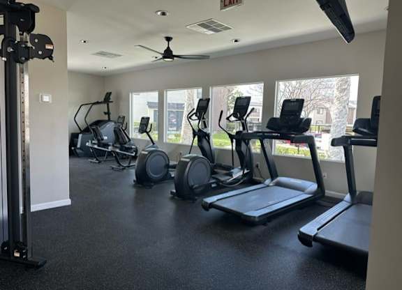 a gym with cardio equipment and windows in a building at Lincoln Park Apartments, Corona California