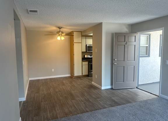 an empty living room and kitchen with a ceiling fan at Lincoln Park Apartments, California