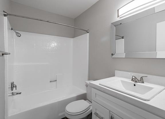 A white bathroom with a toilet, sink, and shower at Lincoln Park Apartments, Corona, 92882