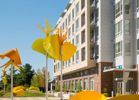 a city street with yellow sculptures in front of an apartment building at The Metropolitan Downtown Columbia, Maryland