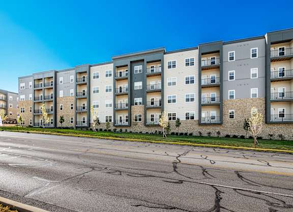 A row of modern apartment buildings with a cracked street in front.