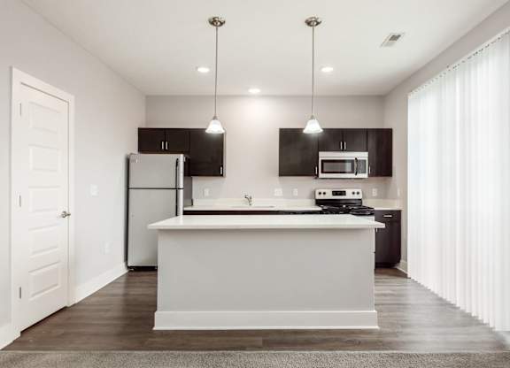 A modern kitchen with a white island and dark brown cabinets.