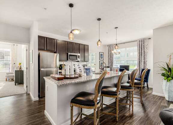 A kitchen with a white island and black chairs.