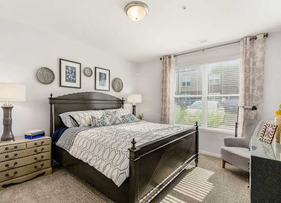A bedroom with a large bed, a nightstand, and a chair.