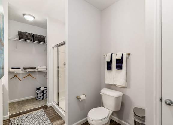 A white bathroom with a toilet, towel rack, and a mirror.