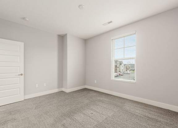 A room with a white door and a window with blinds.