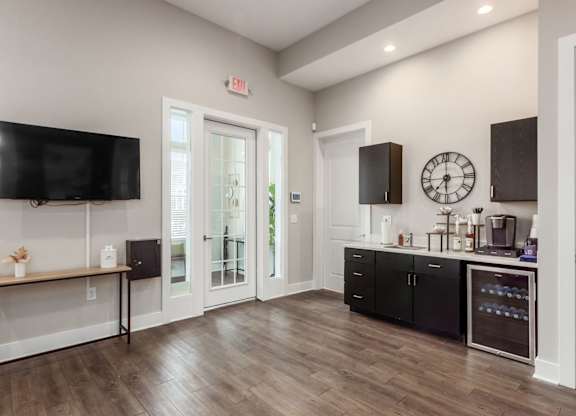 A kitchen with black cabinets and a wooden floor.