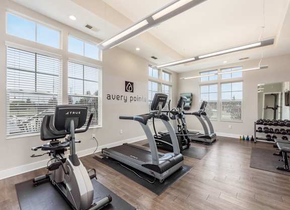 Avery Point fitness room with treadmills, elliptical machines, and dumbbells.