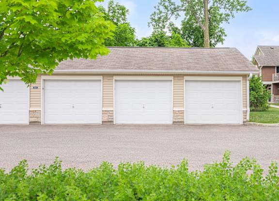 A two-car garage with a brown roof is surrounded by greenery.