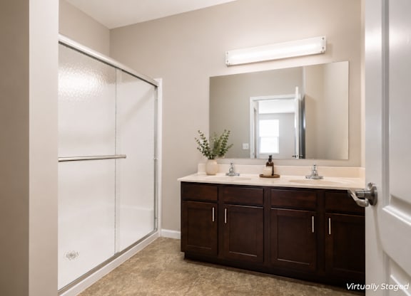 A bathroom with a brown vanity and a white shower.