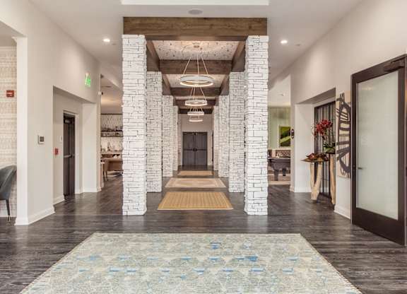 A hallway with a rug in the middle and a fireplace on the left.