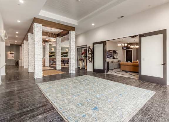 A large room with a rug on the floor and a staircase on the left side.