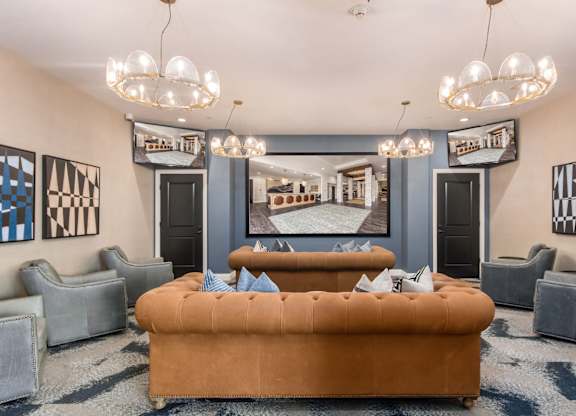 A living room with a brown sofa and grey chairs.