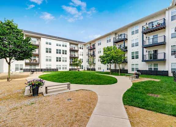 A sunny day at a residential complex with a walkway and green grass.