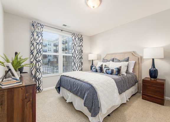 A bedroom with a bed, nightstands, and a window with curtains.