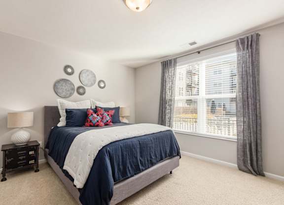 A bedroom with a large bed and a window with curtains.