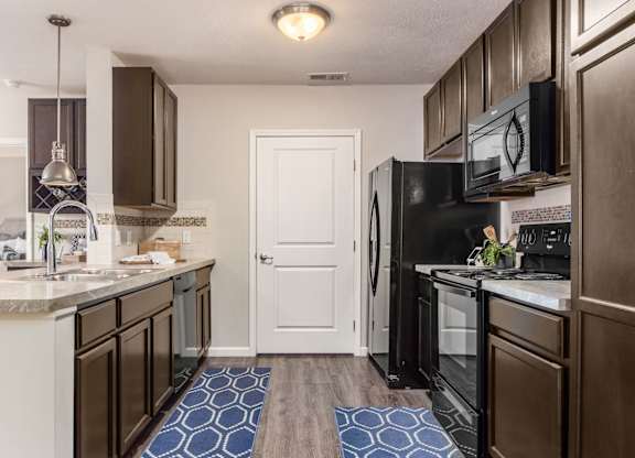 A kitchen with brown cabinets and a black refrigerator.