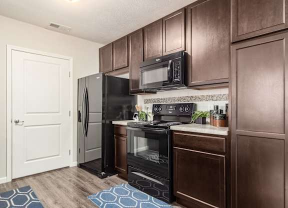 A kitchen with brown cabinets and black appliances.