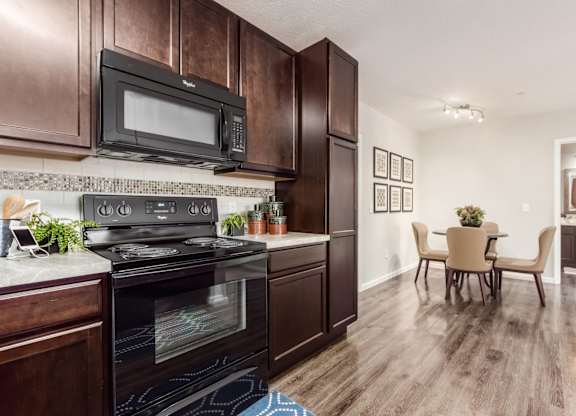 A kitchen with dark wood cabinets and a black stove top oven.