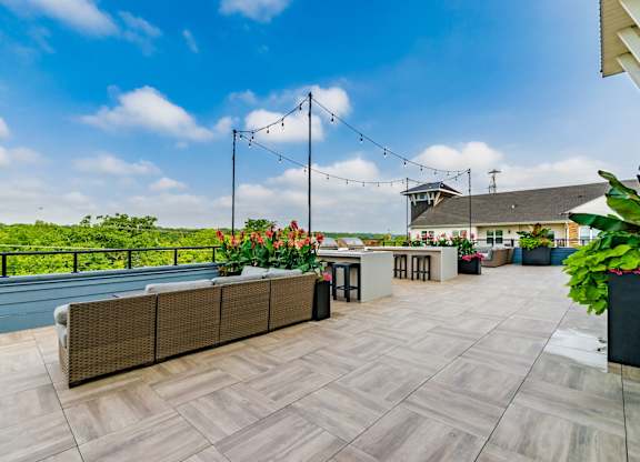 A rooftop patio with a long table and chairs overlooking a body of water.