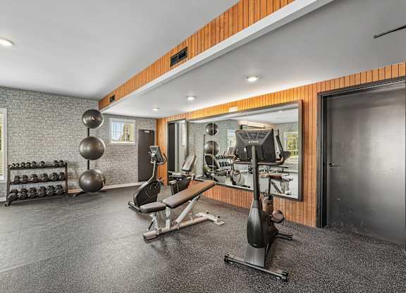 A gym with a variety of equipment including a weight bench, a leg press machine, and a squat rack.
