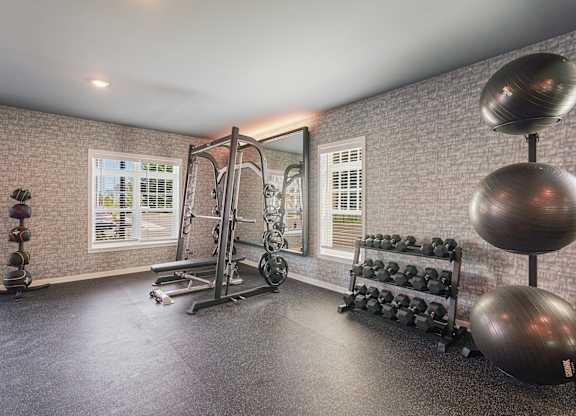 A home gym with a variety of equipment including a weight bench, dumbbells, and a mirror.